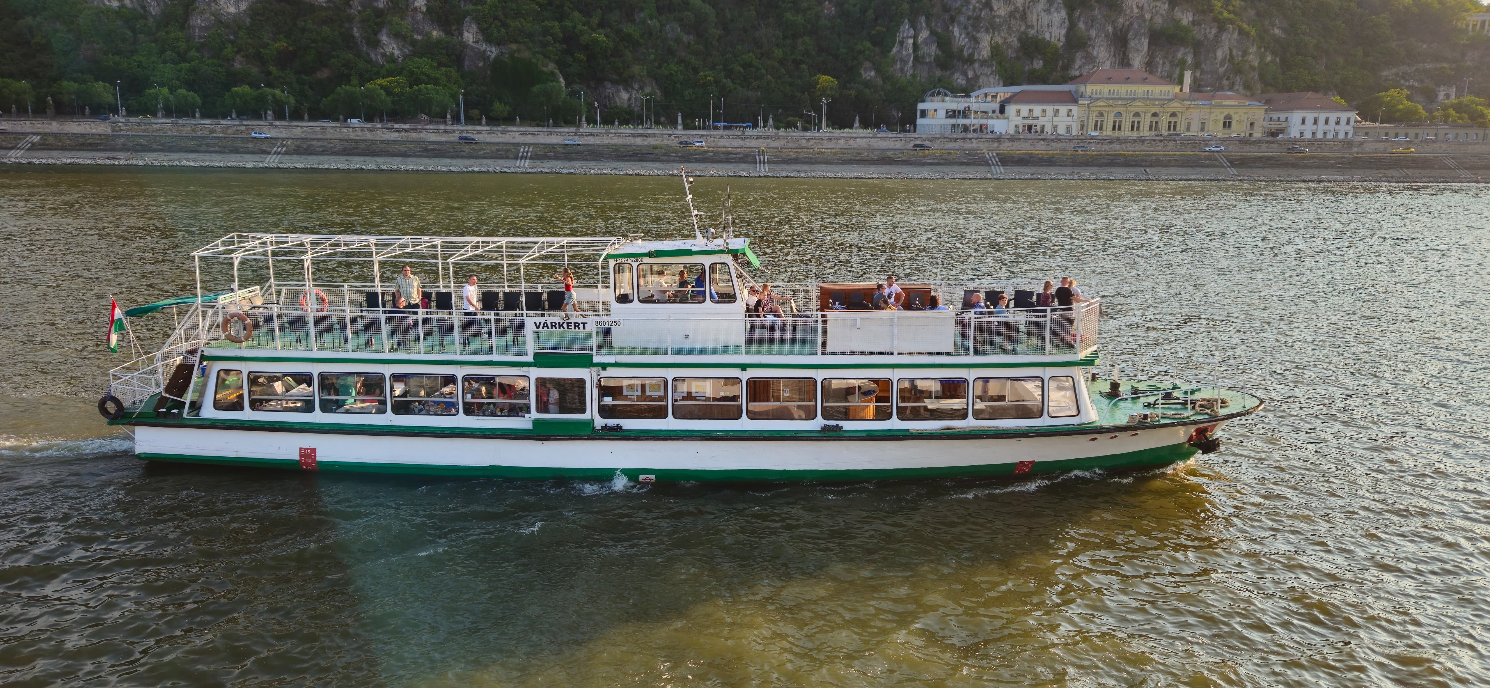 The authentic BudapestPort retro boat sailing on the Danube river with Gellért Hill in the background